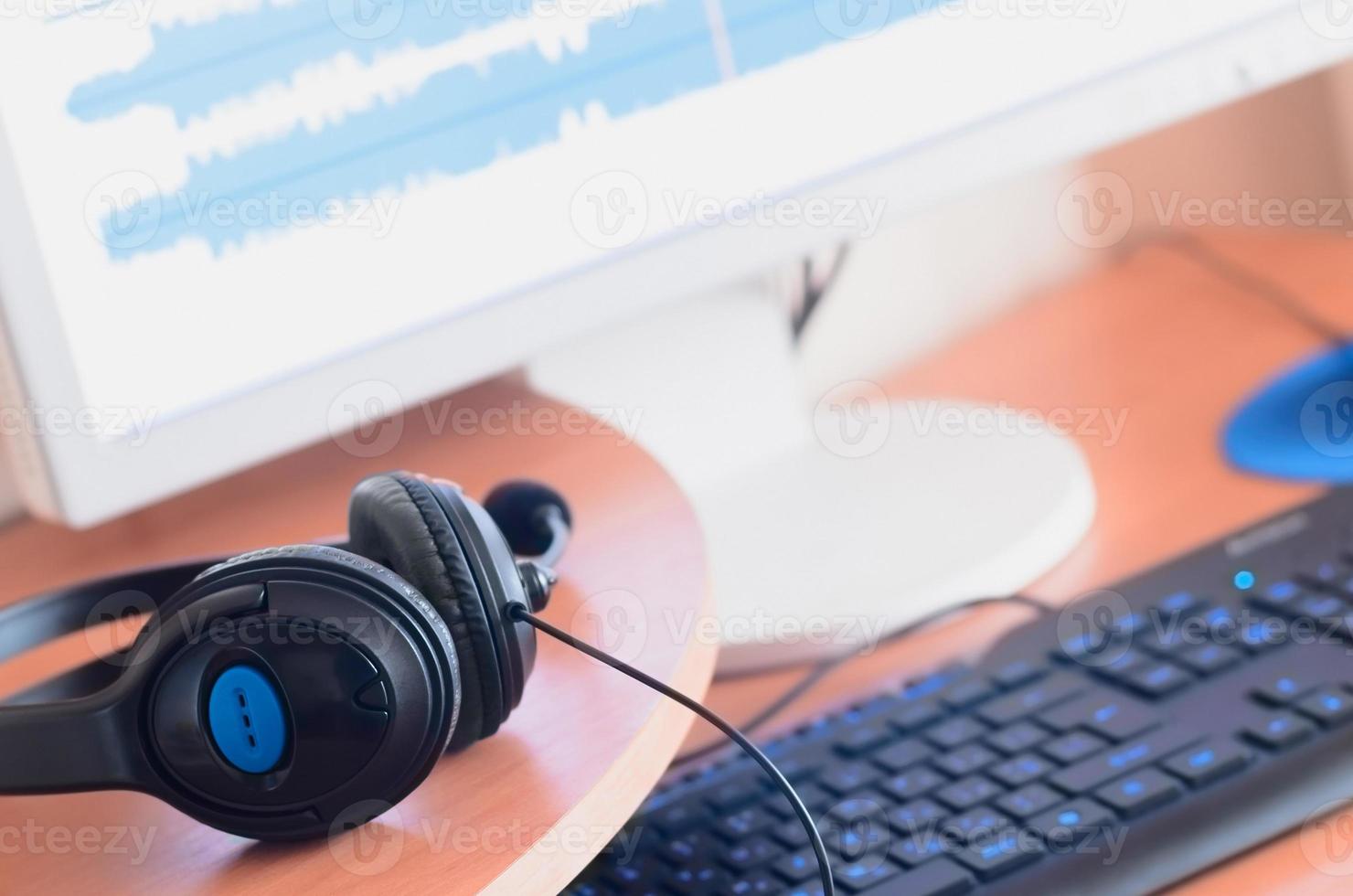 Big black headphones lie on the wooden desktop of the sound designer photo