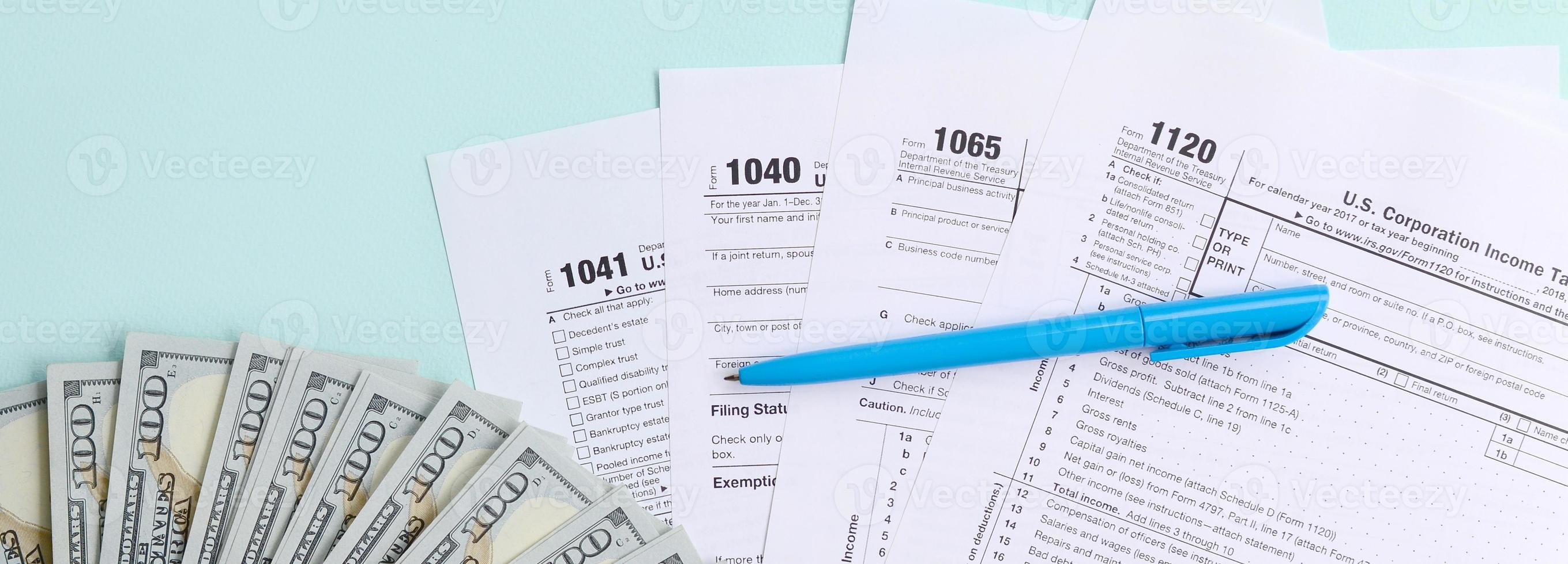 Tax forms lies near hundred dollar bills and blue pen on a light blue background. Income tax return photo