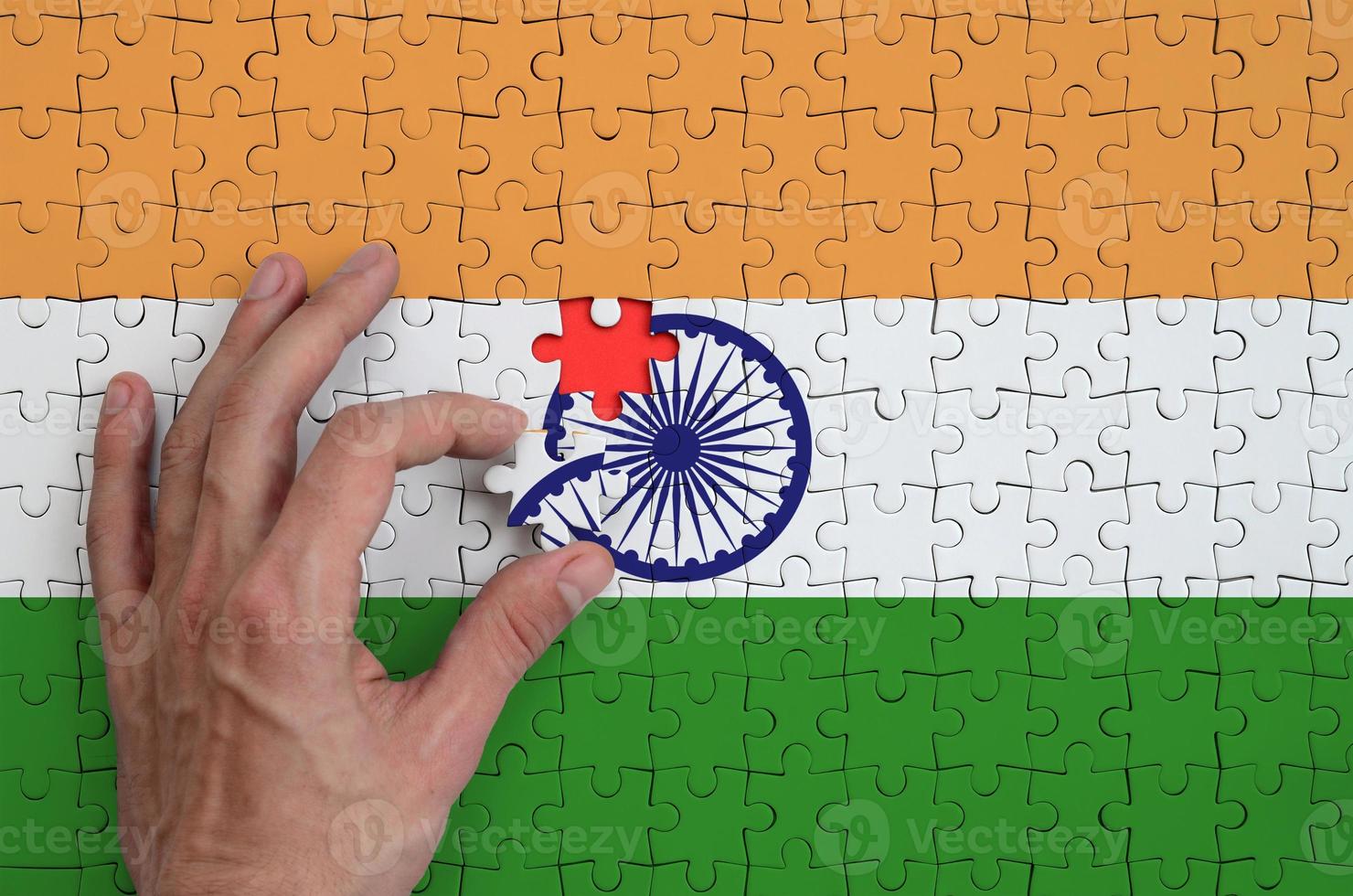 India flag is depicted on a puzzle, which the man's hand completes to fold photo