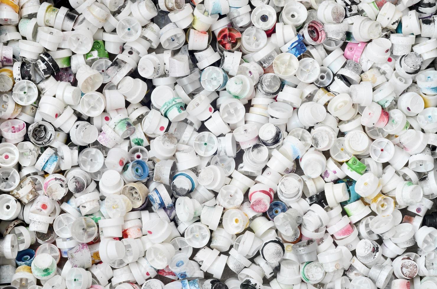 A pattern of many used and soiled nozzles from spray cans with aerosol paint. Background texture of the street art of drawing graffiti on the walls photo