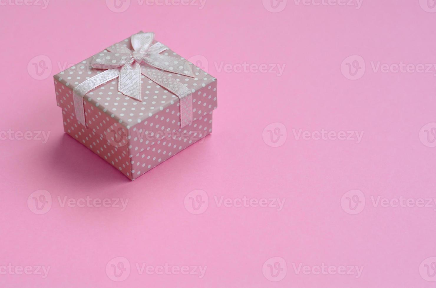 Small pink gift box lie on texture background of fashion pastel pink color paper in minimal concept photo