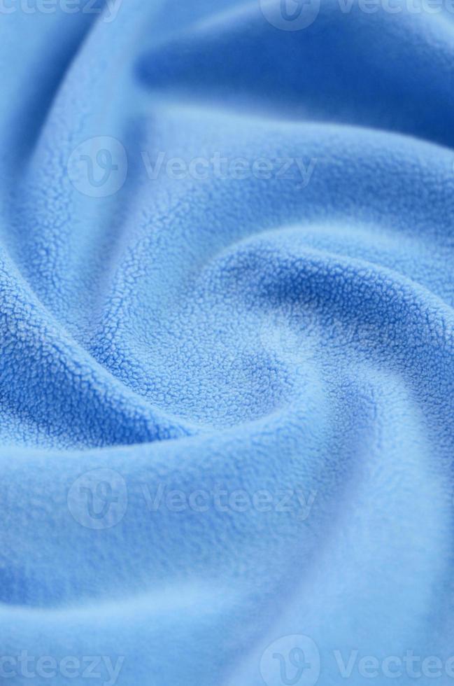 The blanket of furry blue fleece fabric. A background of light blue soft plush fleece material with a lot of relief folds photo