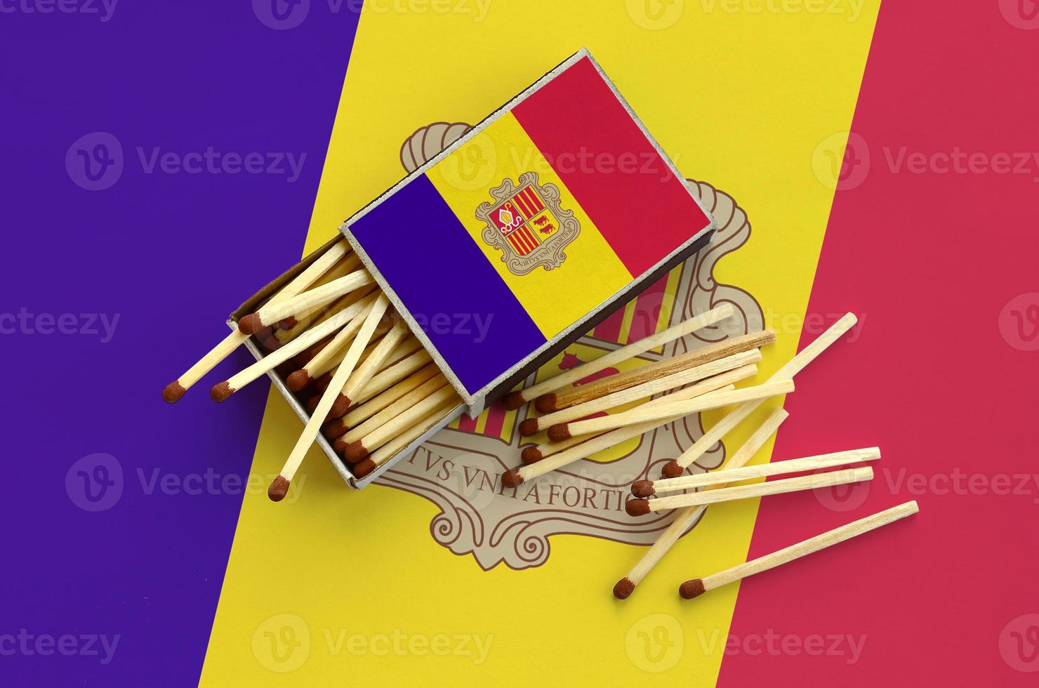 Andorra flag is shown on an open matchbox, from which several matches fall and lies on a large flag photo