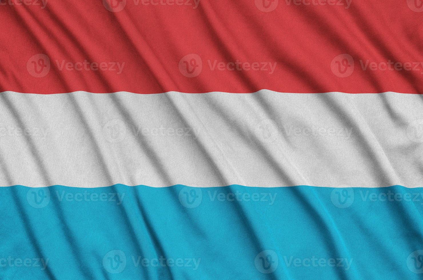 Luxembourg flag is depicted on a sports cloth fabric with many folds. Sport team banner photo