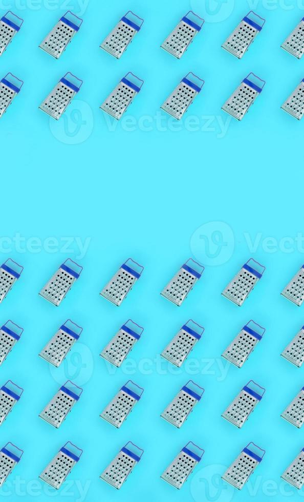 Small stainless steel graters lies on a pastel colored paper. Kitchen accessories. Tools for cooking. Flat lay top view photo