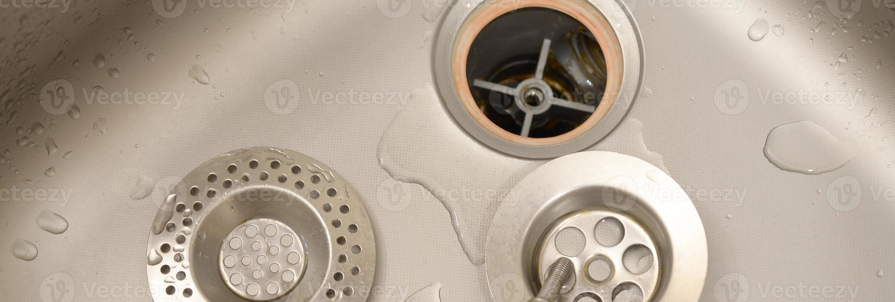 Silvery kitchen sink with a disassembled protective filter during the repair process photo