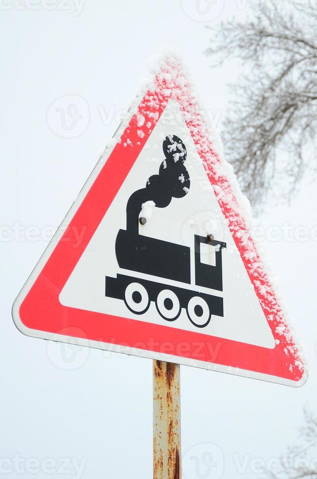 Railway crossing without barrier. A road sign depicting an old black locomotive, located in a red triangle photo