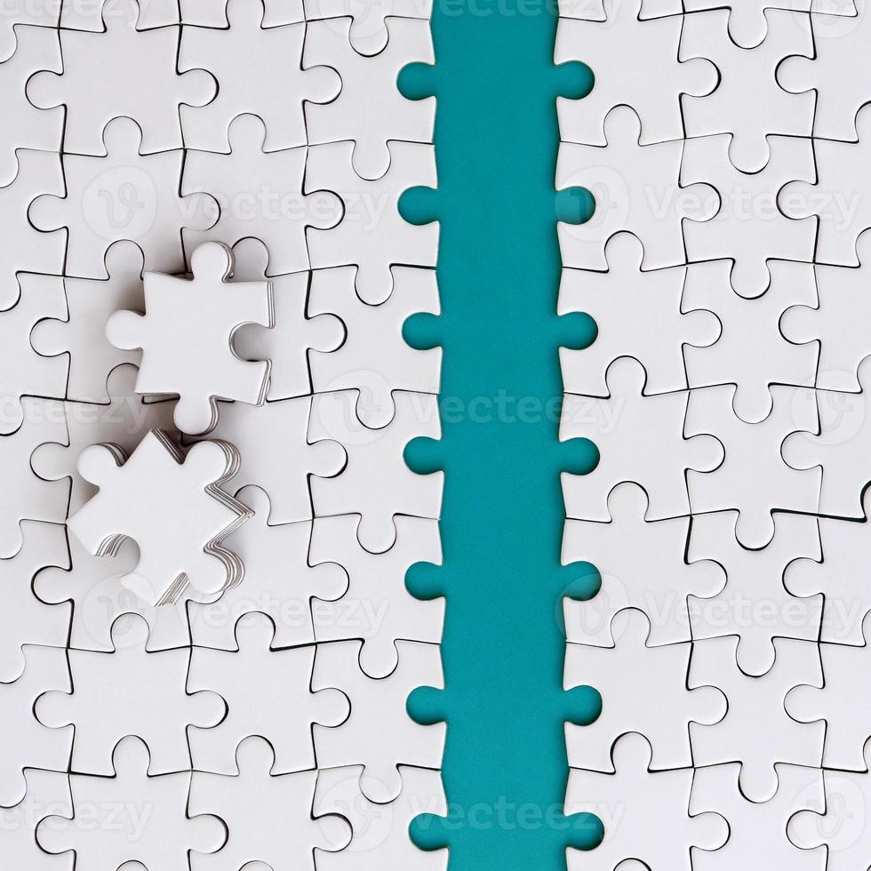 The blue path is laid on the platform of a white folded jigsaw puzzle. The missing elements of the puzzle are stacked nearby. Texture image with space for text photo