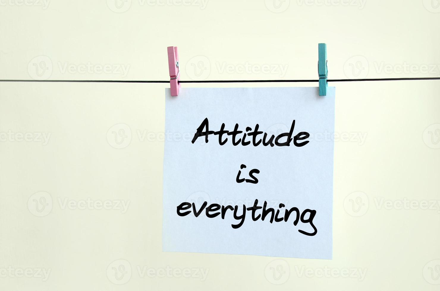 Attitude is everything. Note is written on a white sticker that hangs with a clothespin on a rope on a background of beige wall photo
