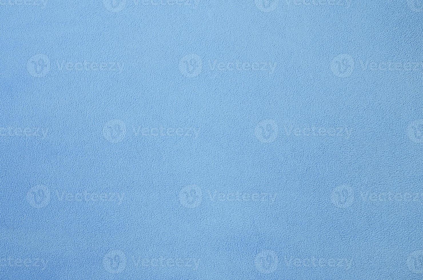 The blanket of furry blue fleece fabric. A background texture of light blue soft plush fleece material photo