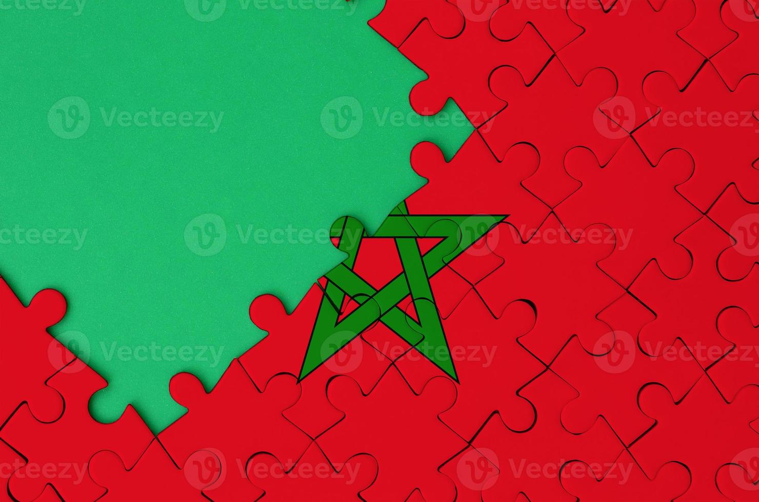 Morocco flag is depicted on a completed jigsaw puzzle with free green copy space on the left side photo