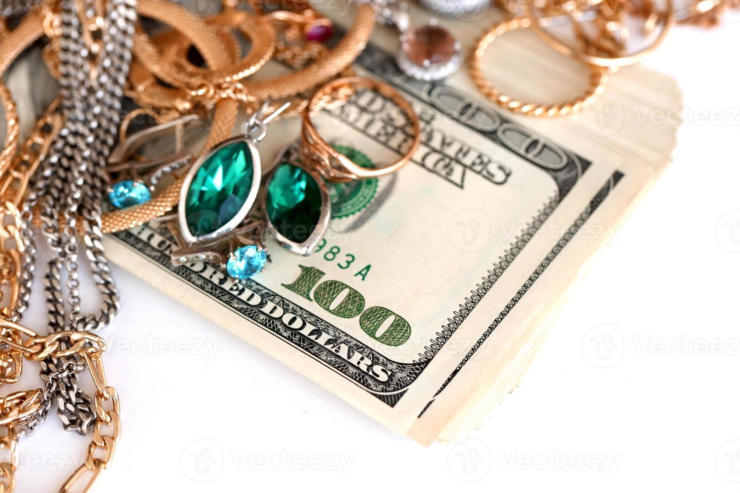 Many expensive golden and silver jewerly rings, earrings and necklaces with big amount of US dollar bills on white background. Pawnshop or jewerly shop photo