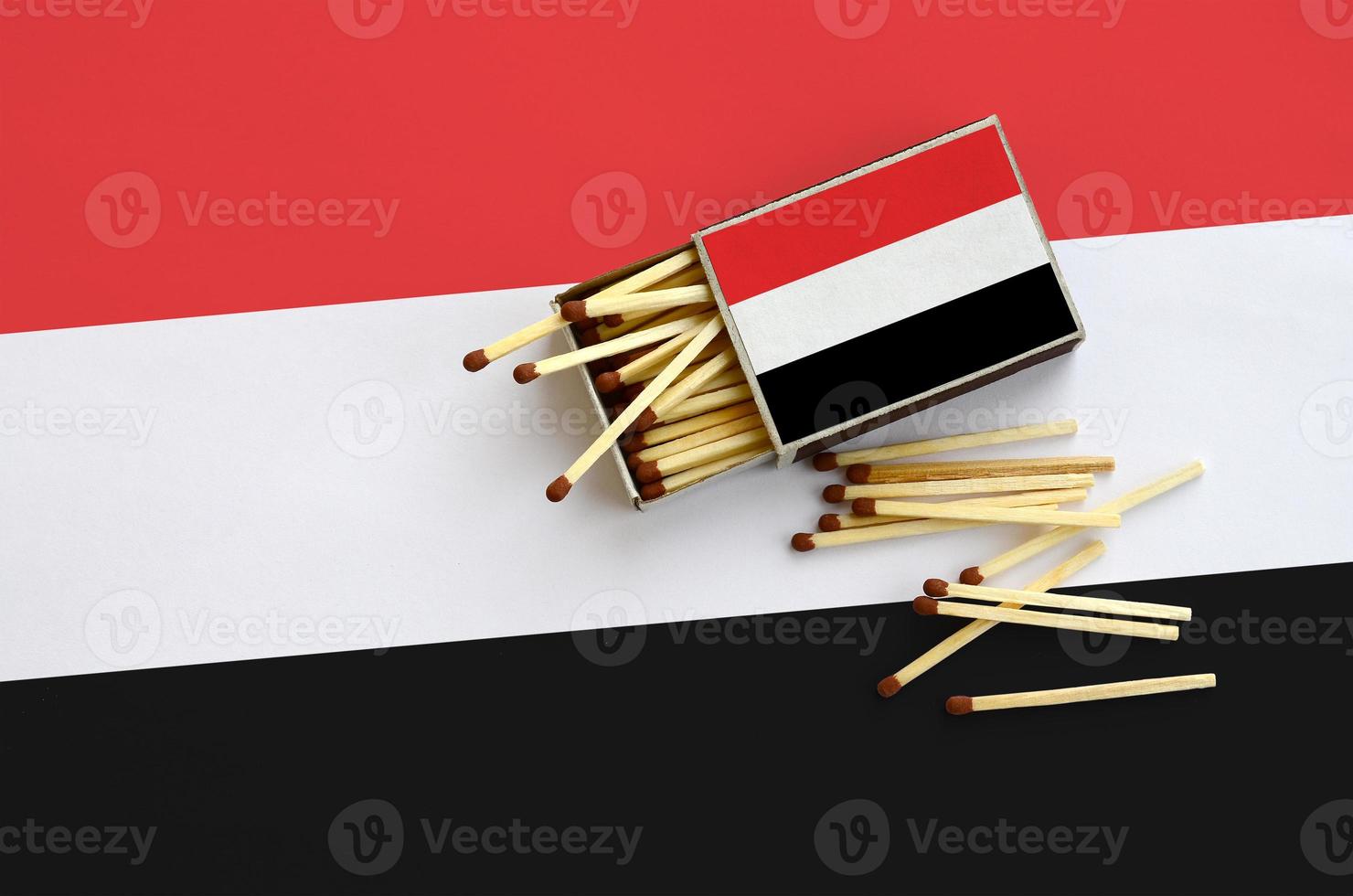 Yemen flag is shown on an open matchbox, from which several matches fall and lies on a large flag photo