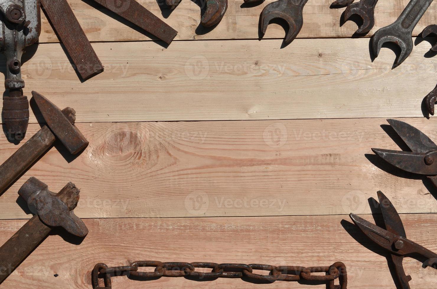 A set of old and rusty tools lies on a wooden table in the workshop photo