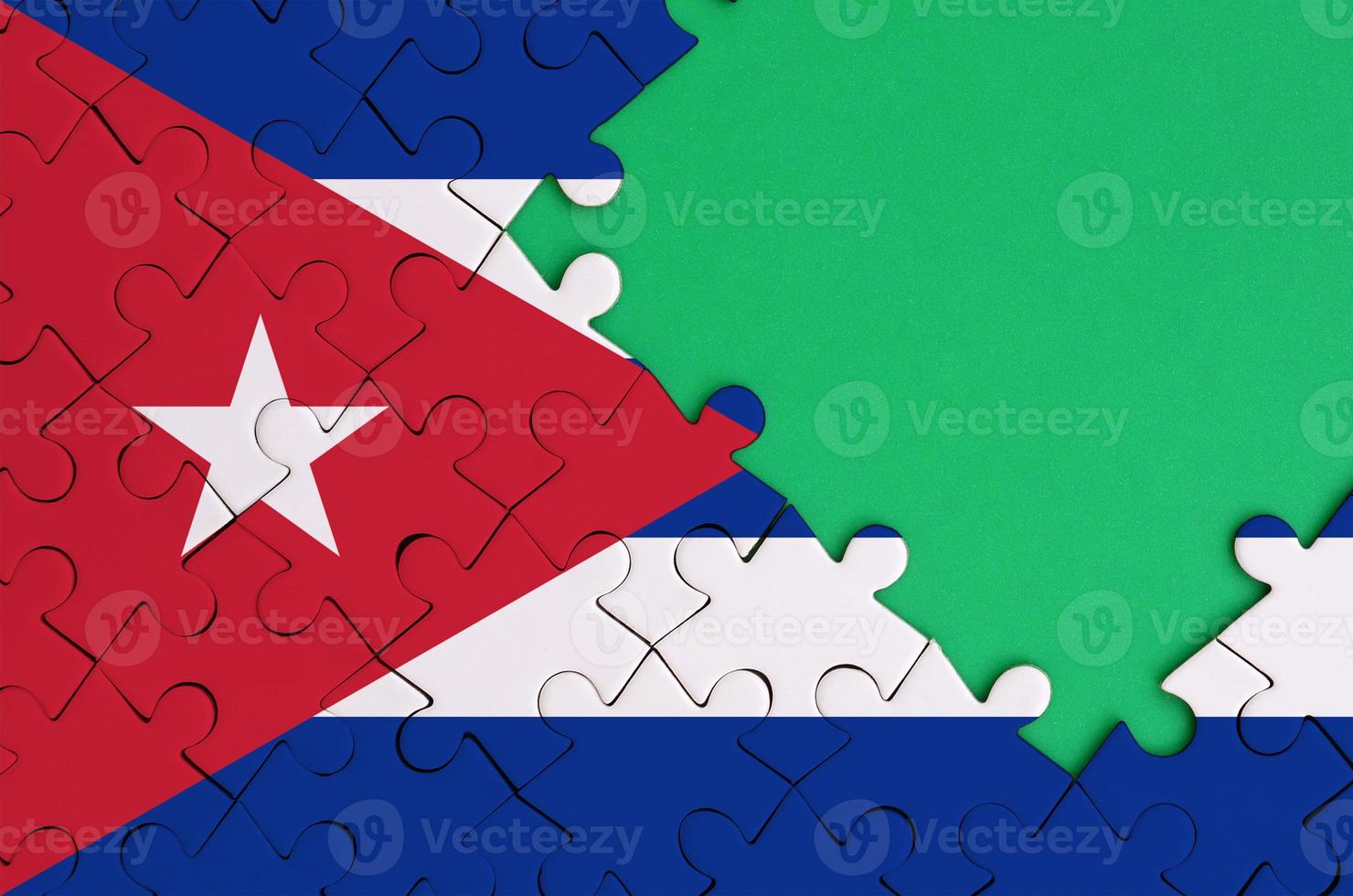 Cuba flag is depicted on a completed jigsaw puzzle with free green copy space on the right side photo