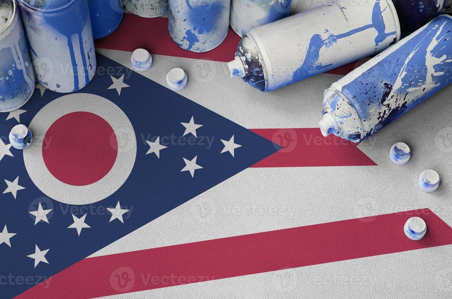 Ohio US state flag and few used aerosol spray cans for graffiti painting. Street art culture concept photo