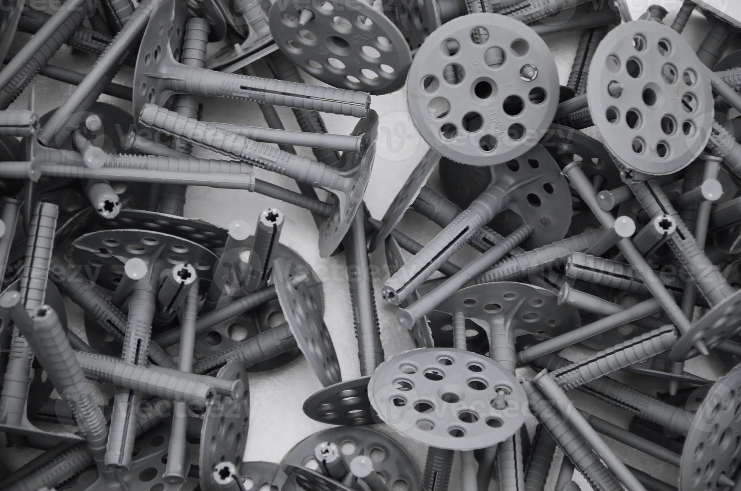 Background pattern of many gray plastic dowels fastening for thermal insulation. A huge pile of fixtures for the installation of expanded polystyrene plates for the insulation of the building walls photo