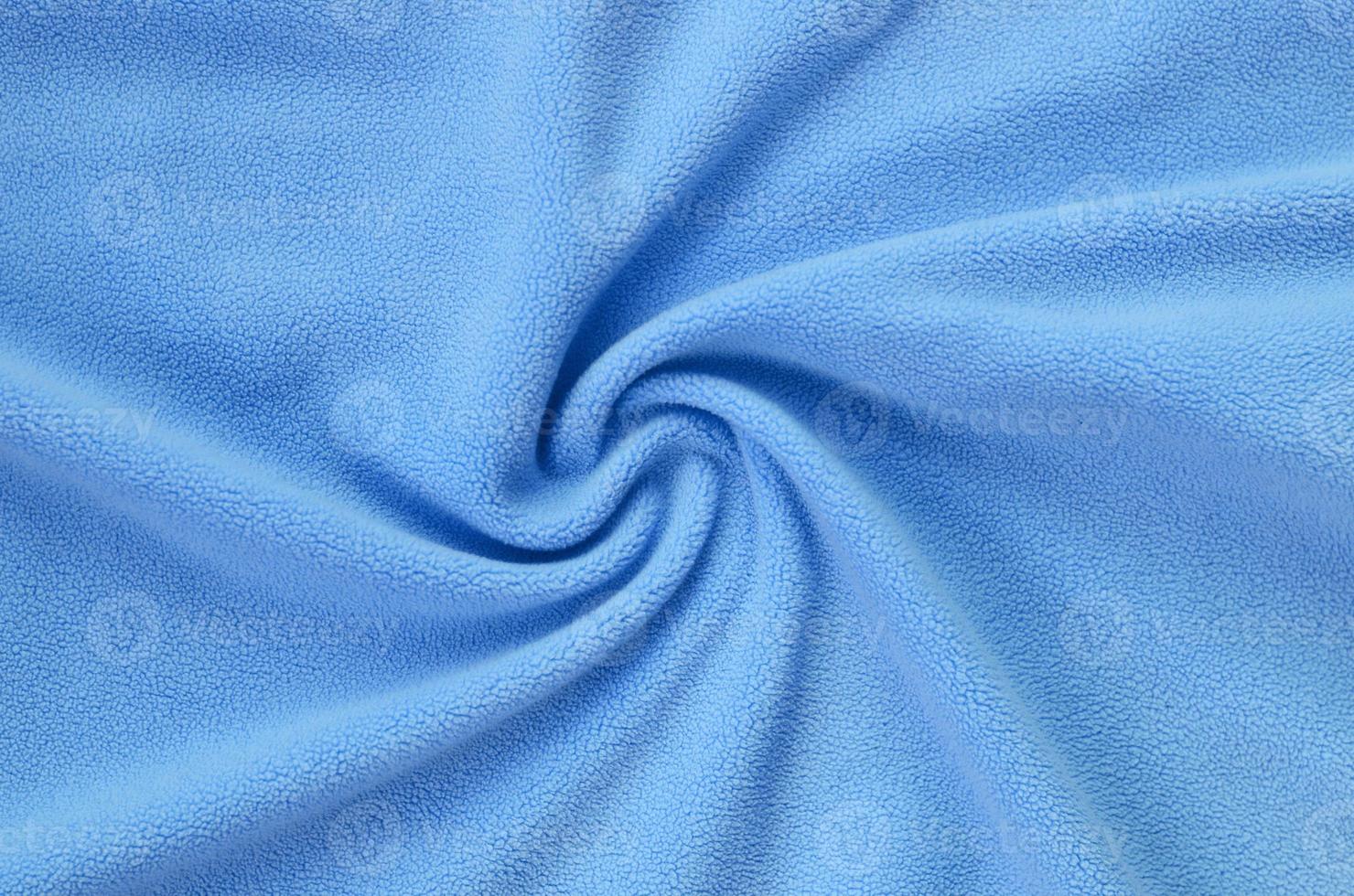 The blanket of furry blue fleece fabric. A background of light blue soft plush fleece material with a lot of relief folds photo