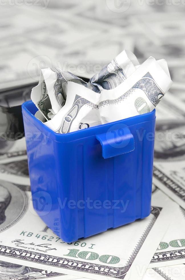 American cash notes are thrown into the trash bin on a multitude of hundred dollar bills photo