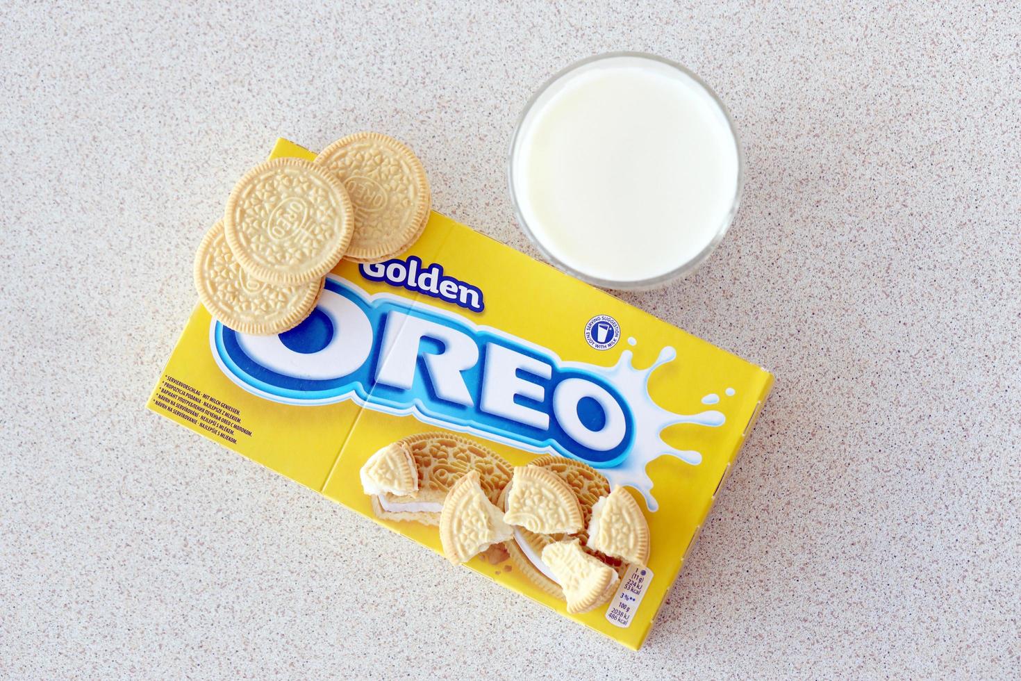 TERNOPIL, UKRAINE - MAY 28, 2022 Oreo golden crispy cookies with glass of milk on white background. The brand Oreo is owned by company Mondelez international photo