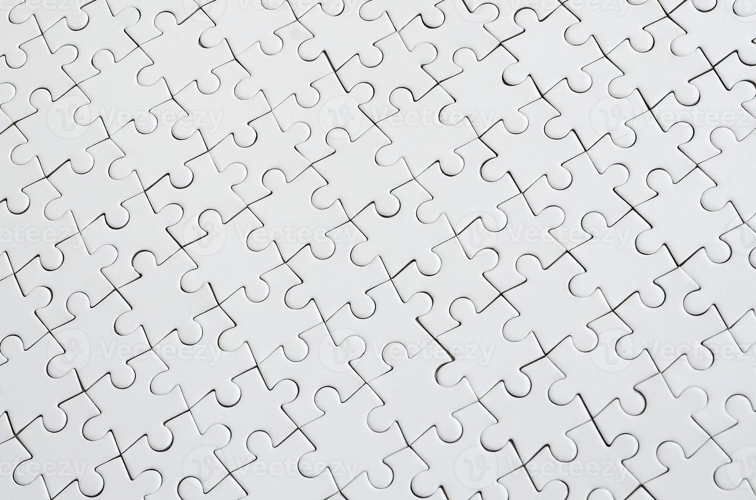Close up texture of a white jigsaw puzzle in assembled condition. Top view. Many components of a large whole mosaic are united photo