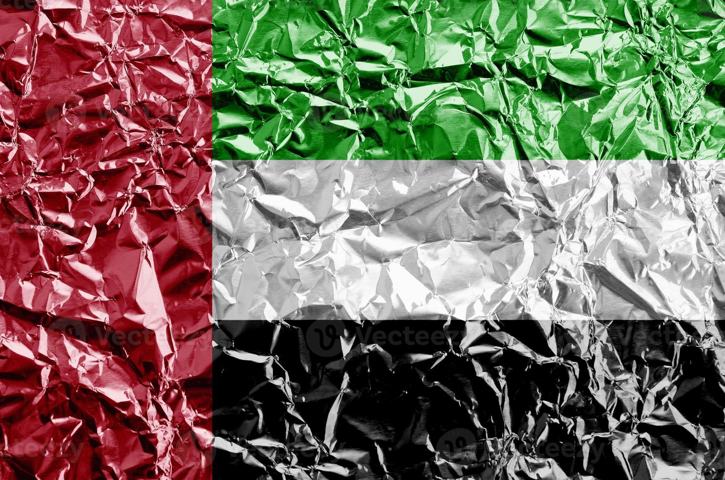 United Arab Emirates flag depicted in paint colors on shiny crumpled aluminium foil closeup. Textured banner on rough background photo