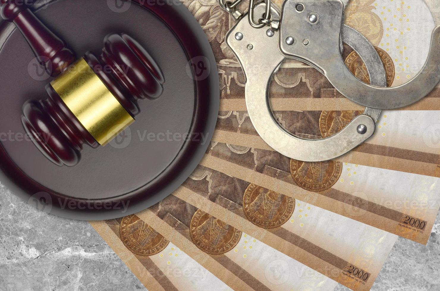 2000 Hungarian forint bills and judge hammer with police handcuffs on court desk. Concept of judicial trial or bribery. Tax avoidance photo