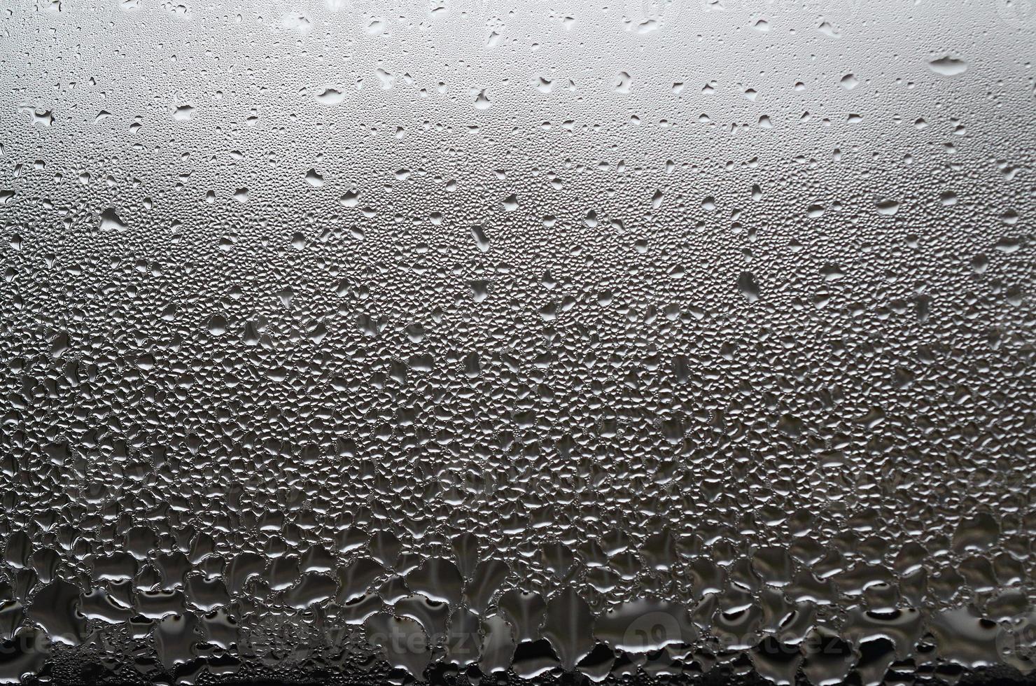 A photo of the glass surface of the window, covered with a multitude of droplets of various sizes. Background texture of a dense layer of condensate on glass