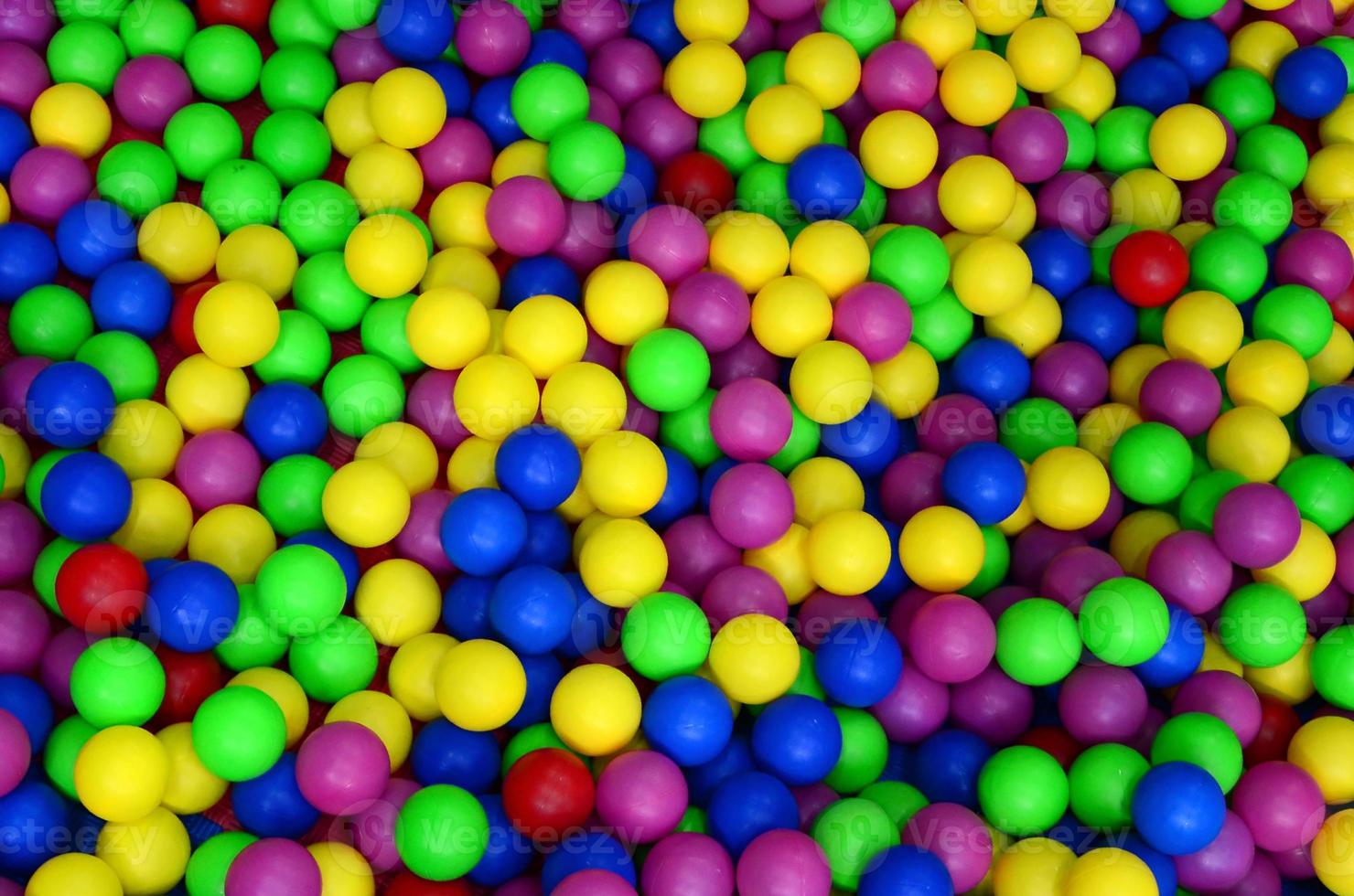 Many colorful plastic balls in a kids' ballpit at a playground. Close up pattern photo