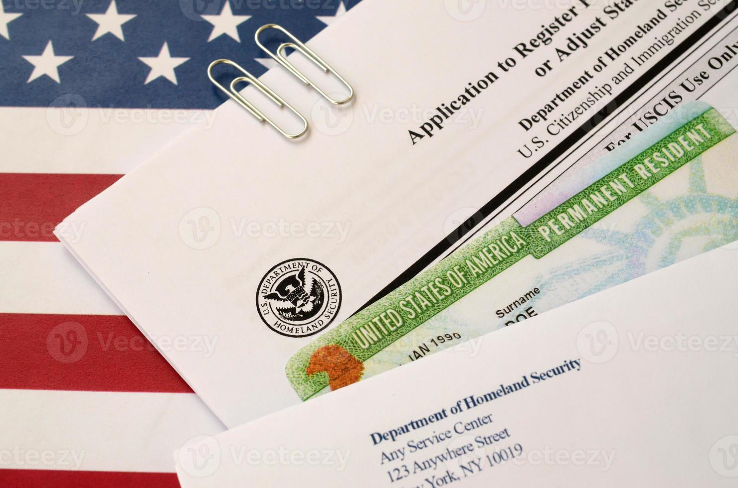 I-485 Application to register permanent residence or adjust status form and green card from dv-lottery lies on United States flag with envelope from Department of Homeland Security photo