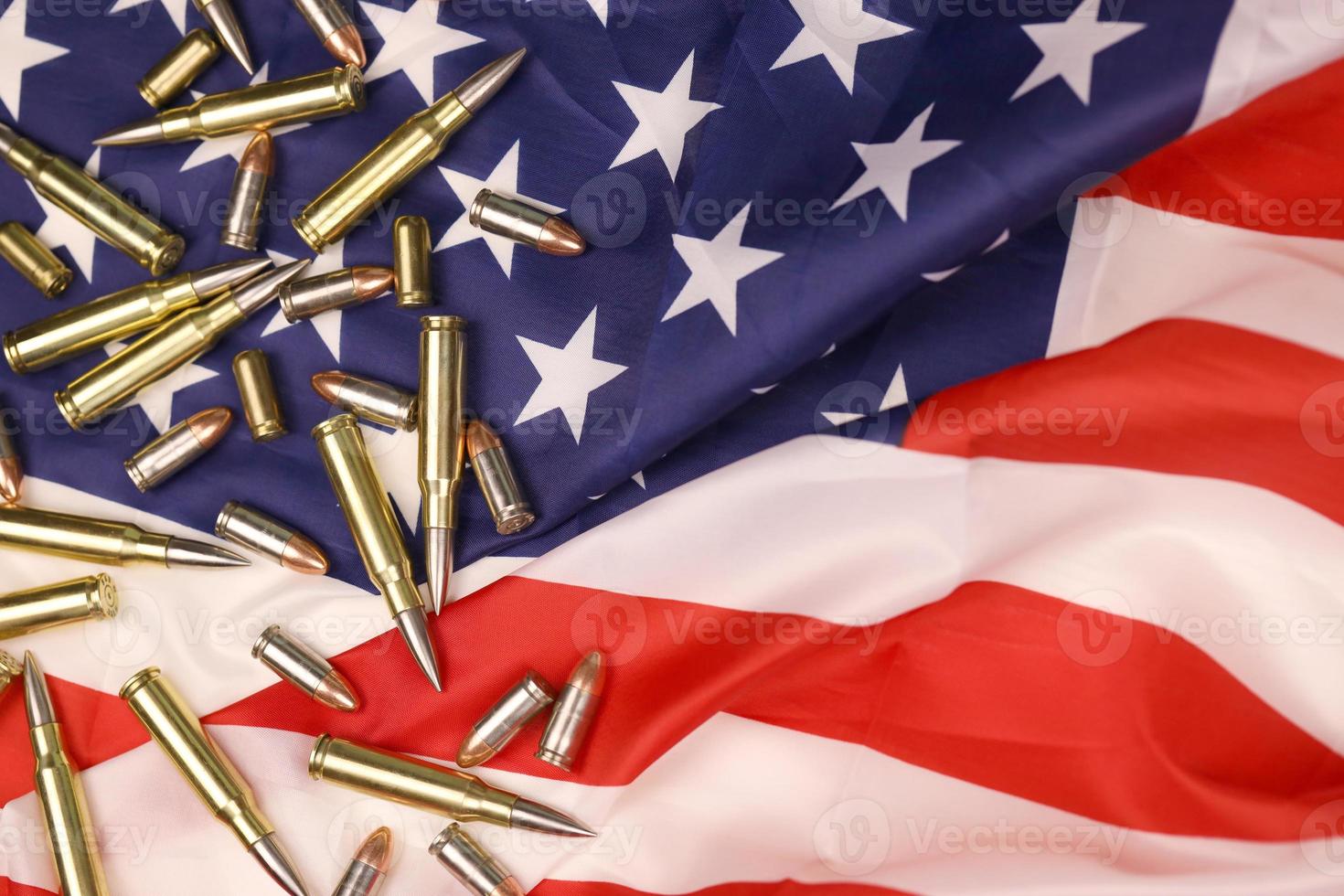 Many yellow 9mm and 5.56mm bullets and cartridges on United States flag. Concept of gun trafficking on USA territory or special ops photo