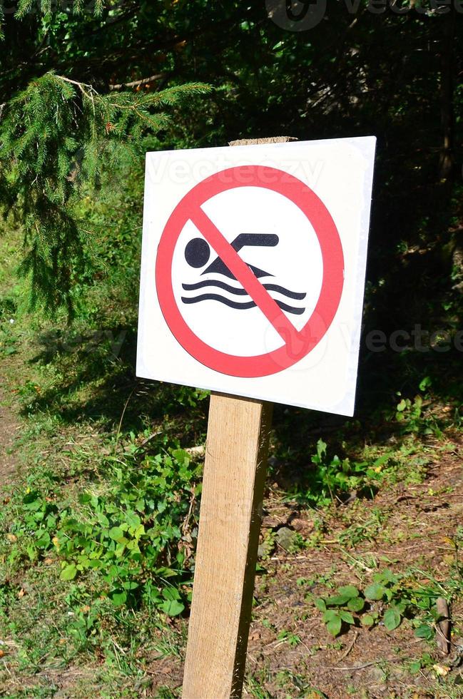 A pillar with a sign denoting a ban on swimming. The sign shows a crossed-out floating person photo