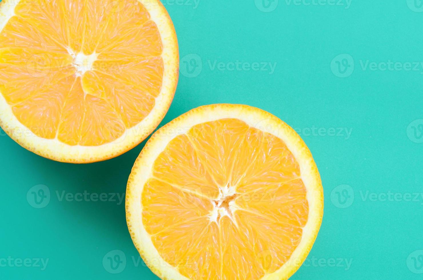 Top view of a several orange fruit slices on bright background in turquoise green color. A saturated citrus texture image photo