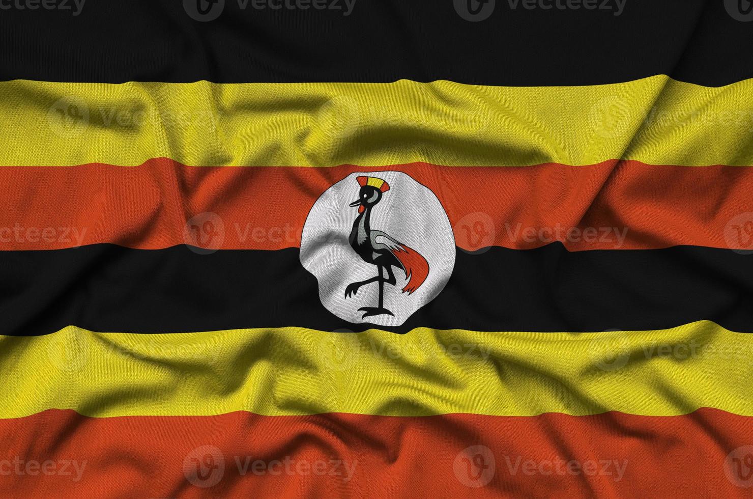 Uganda flag is depicted on a sports cloth fabric with many folds. Sport team banner photo