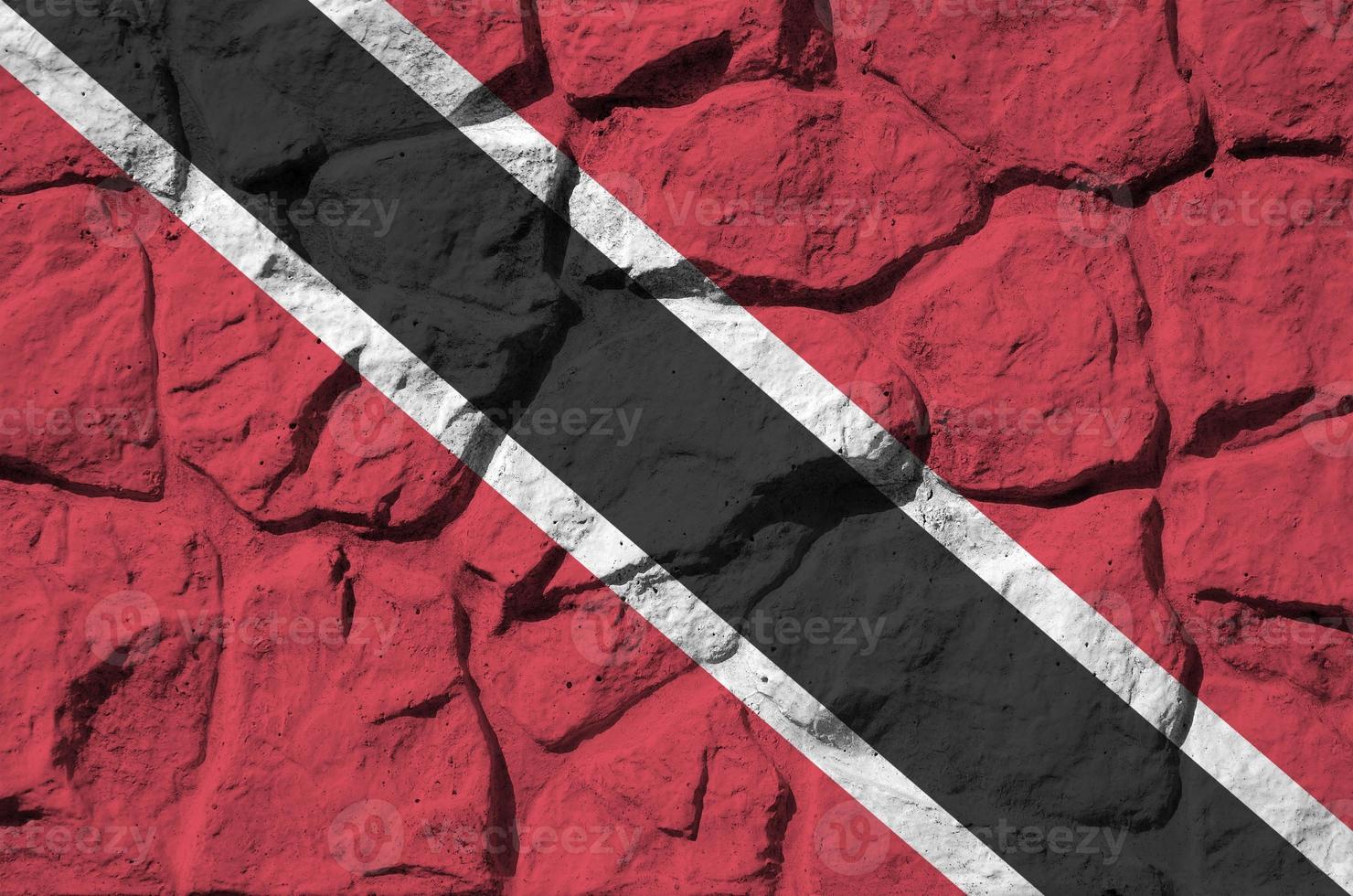 Trinidad and Tobago flag depicted in paint colors on old stone wall closeup. Textured banner on rock wall background photo