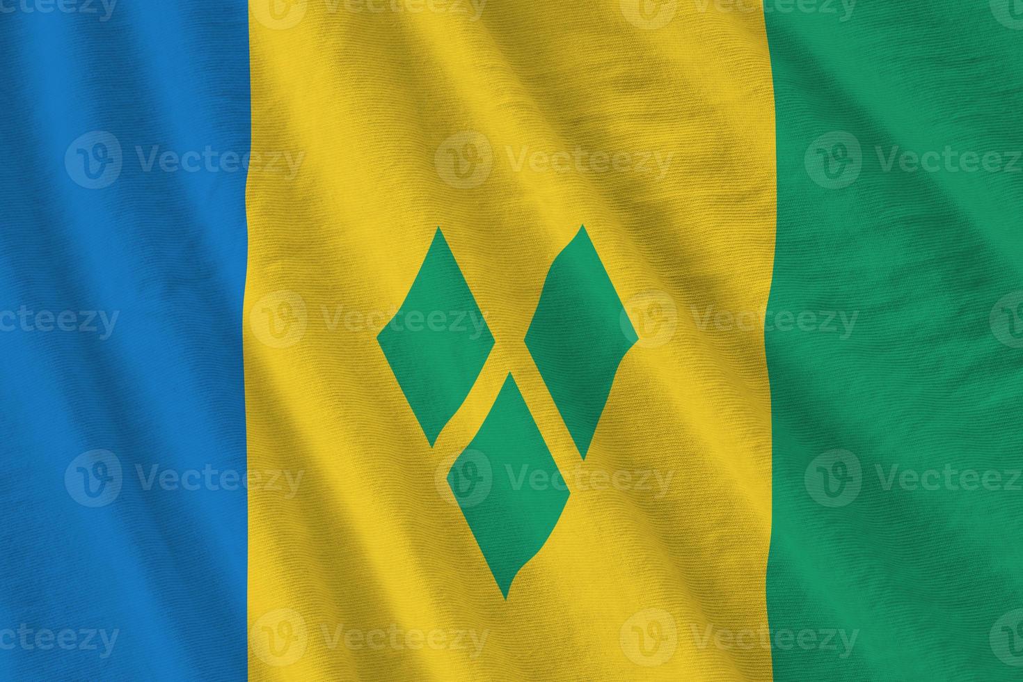 Saint Vincent and the Grenadines flag with big folds waving close up under the studio light indoors. The official symbols and colors in banner photo
