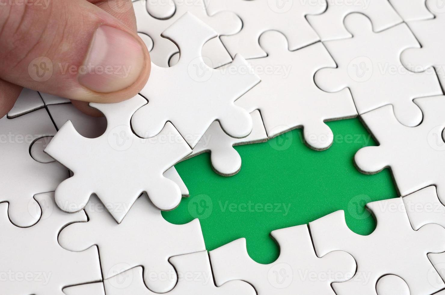 The human hand fills the last missing elements of the surface from the jigsaw puzzle. The concept of the completion of the initiated cases photo