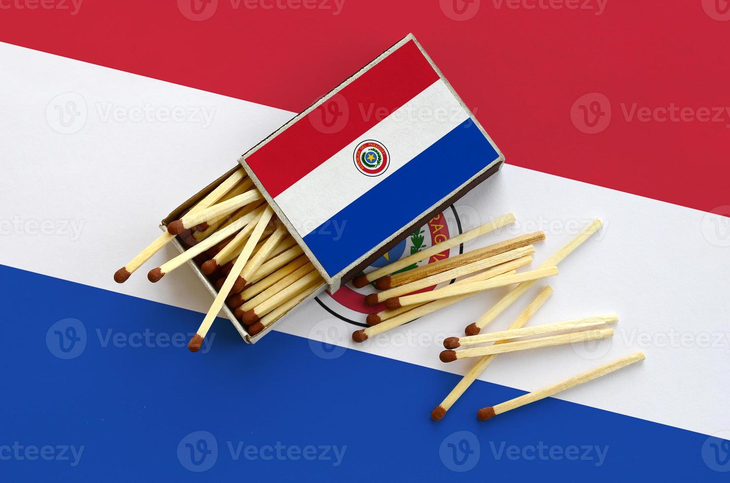 Paraguay flag is shown on an open matchbox, from which several matches fall and lies on a large flag photo