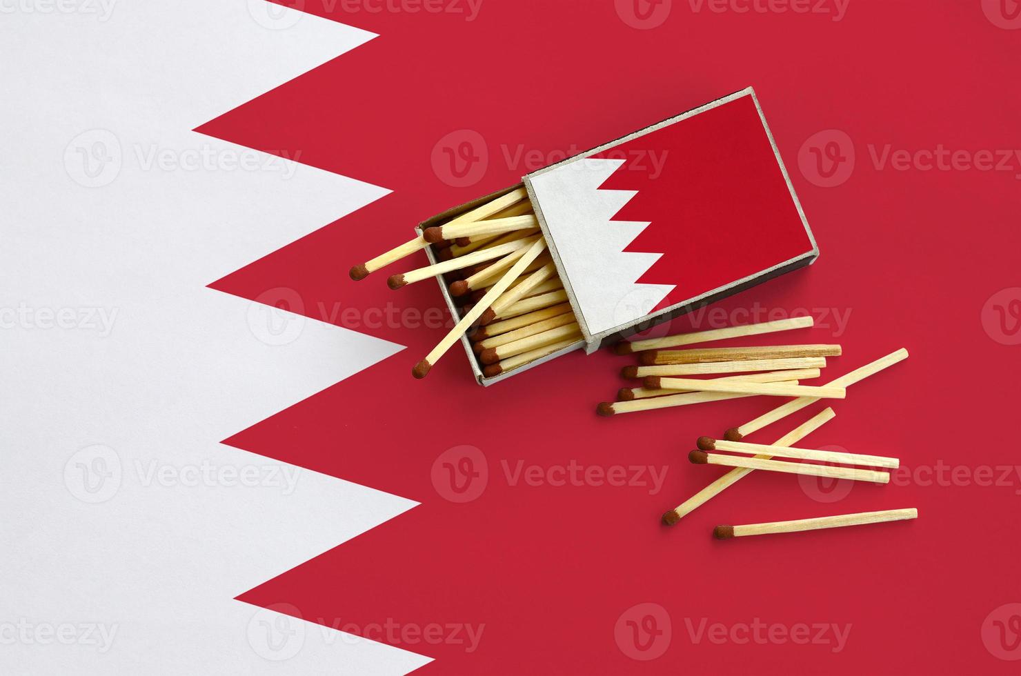 Bahrain flag is shown on an open matchbox, from which several matches fall and lies on a large flag photo