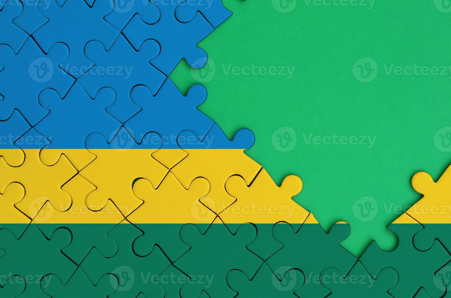 Rwanda flag is depicted on a completed jigsaw puzzle with free green copy space on the right side photo