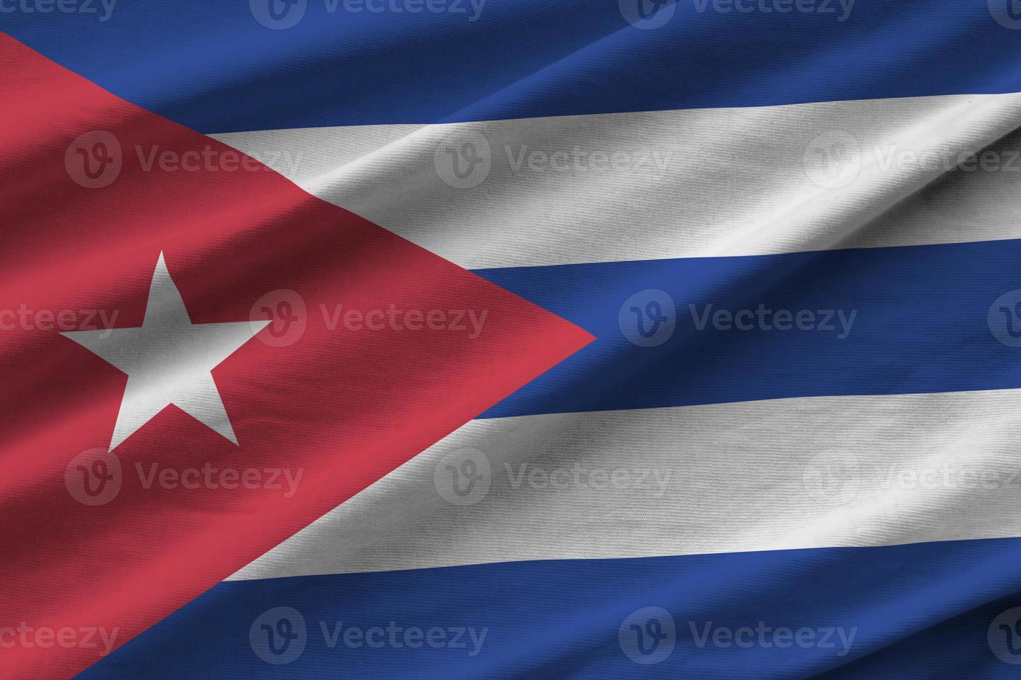 Cuba flag with big folds waving close up under the studio light indoors. The official symbols and colors in banner photo