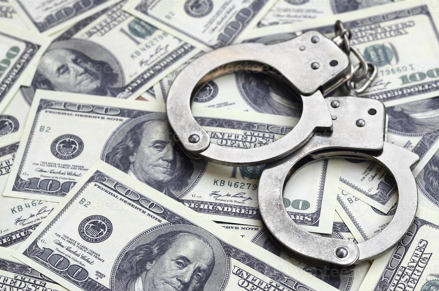 Police handcuffs lie on a lot of dollar bills. The concept of illegal possession of money, illegal transactions with US dollars. Economic Crime photo