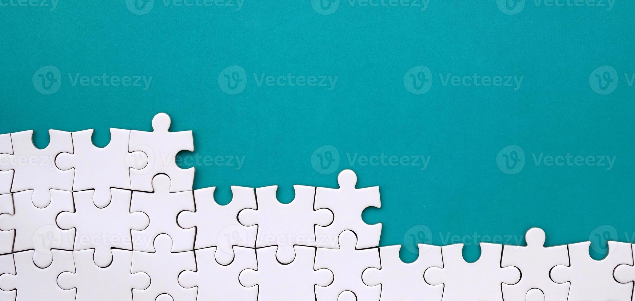 Fragment of a folded white jigsaw puzzle on the background of a blue plastic surface. Texture photo with copy space for text