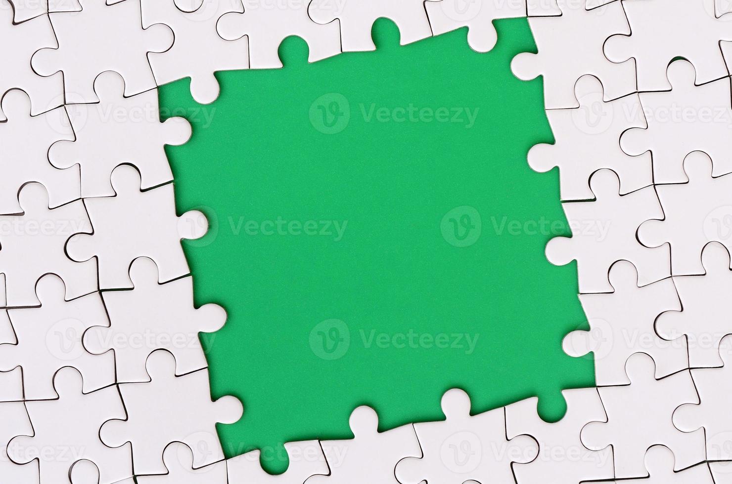 Framing in the form of a rectangle, made of a white jigsaw puzzle around the green space photo