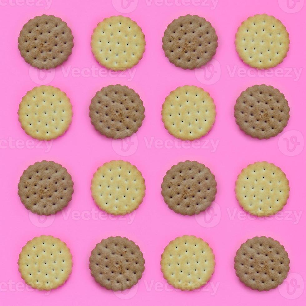 Pattern of a brown biscuits on a pink background. Trendy minimal concept of food and dessert. Abstract flat lay, top view photo
