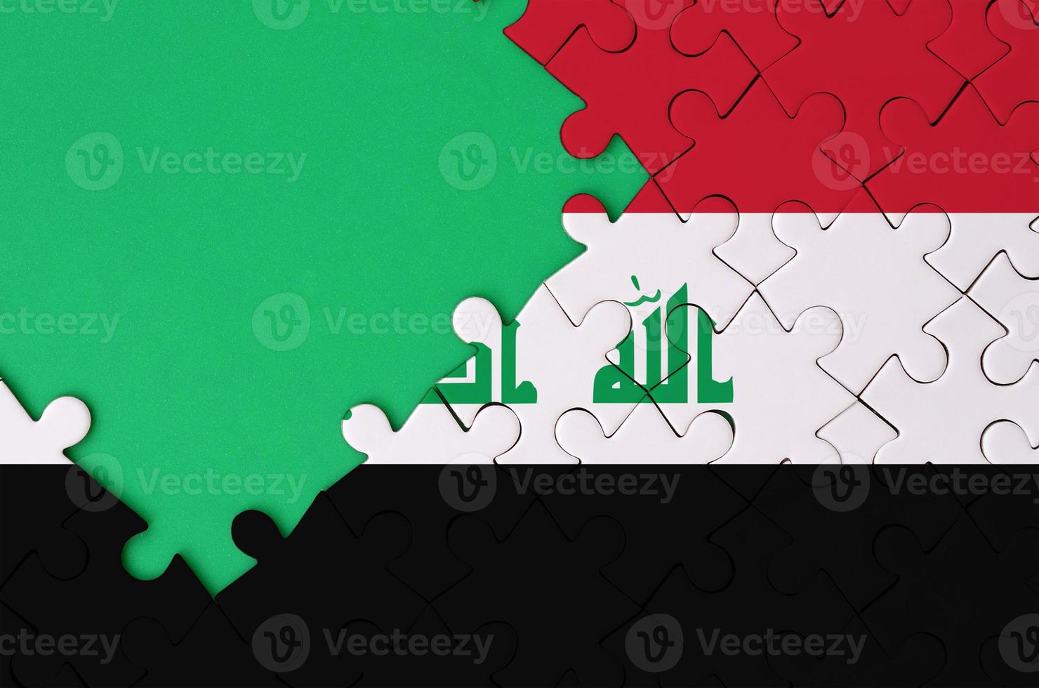 Iraq flag is depicted on a completed jigsaw puzzle with free green copy space on the left side photo