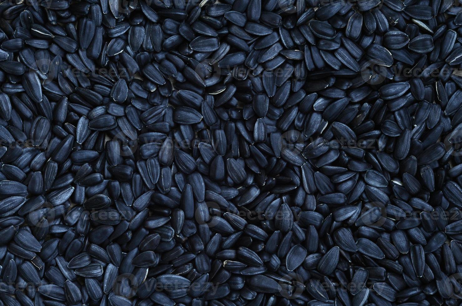 A pattern of many unprocessed fried sunflower seeds in a black shell. photo