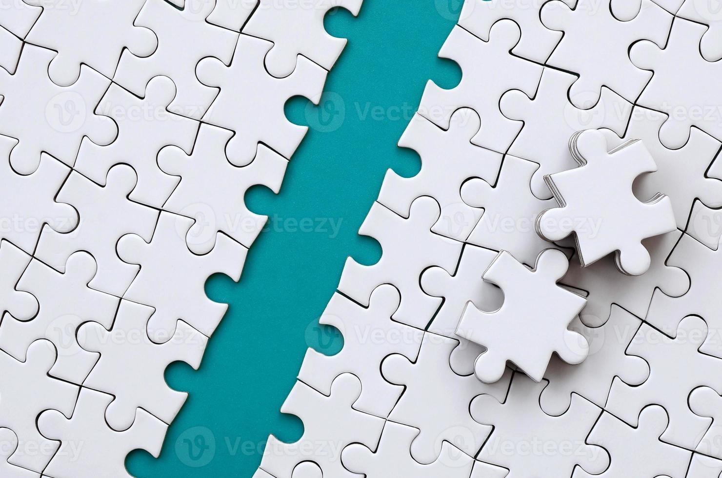 The blue path is laid on the platform of a white folded jigsaw puzzle. The missing elements of the puzzle are stacked nearby. Texture image with space for text photo