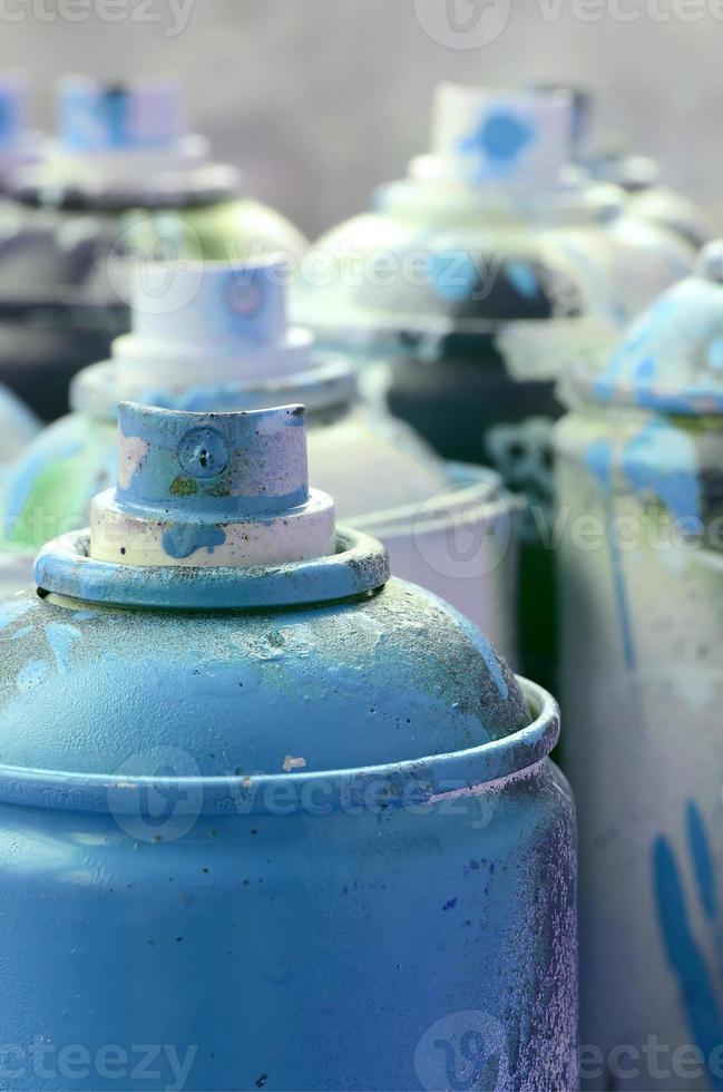 A lot of dirty and used aerosol cans of bright blue paint. Macro photograph with shallow depth of field. Selective focus on the spray nozzle photo