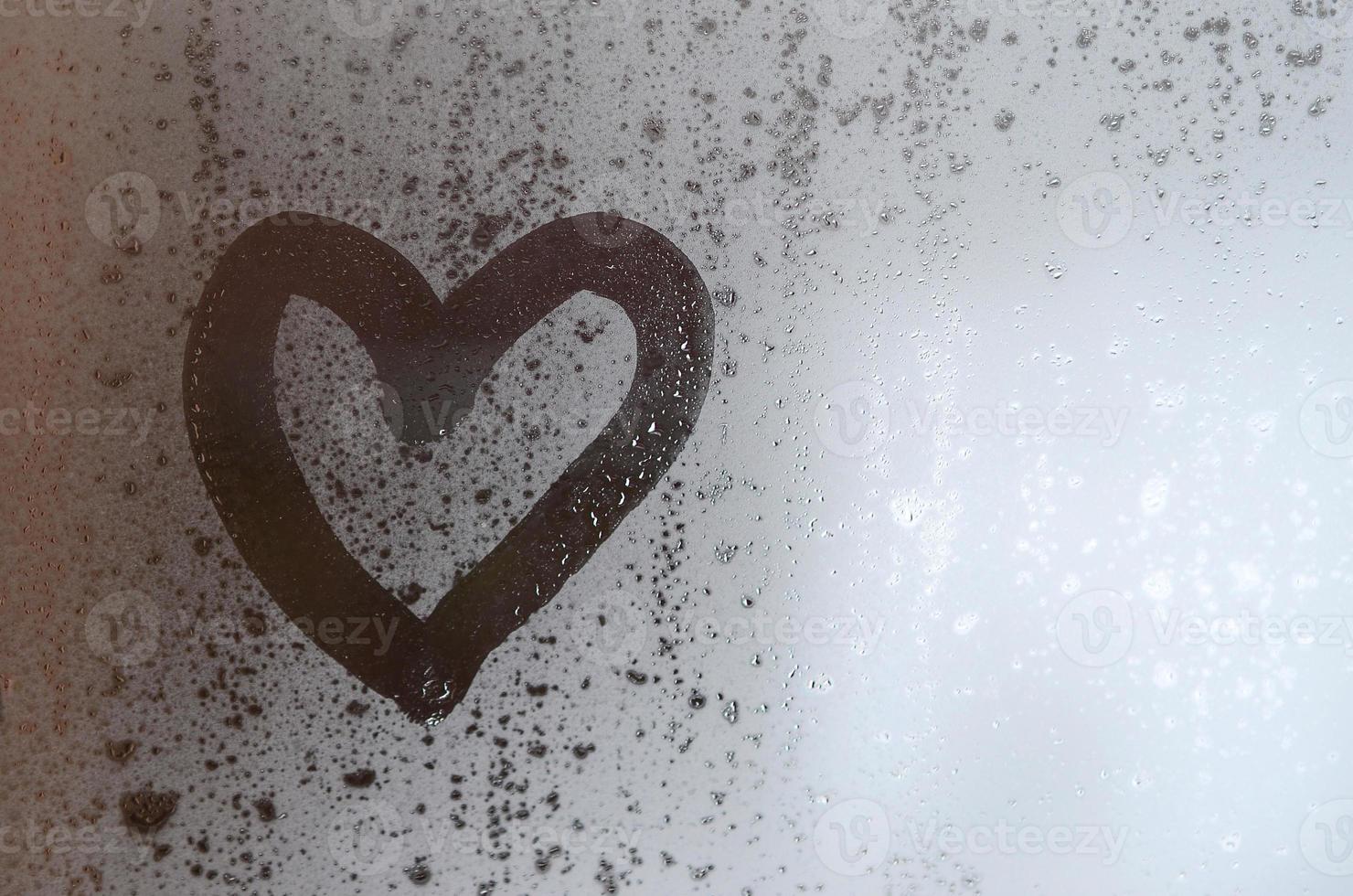 The heart is painted on the misted glass in the winter photo